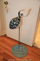 Full front view of standing ceramic pelican sculpture on blue textured base.