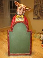 Front view of ceramic pig figurine holding chalkboard menu with red decorative frame.