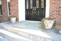 Four large white yard planters arranged on the ground in front of black double doors with brass handles, showing their size and shape.