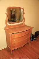 Front and side angled view of wooden dresser with attached mirror showing drawer design and carved details.