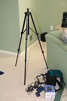 Full view of Velbon Victory 450 tripod standing upright with camera equipment visible on carpet nearby.