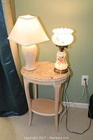 Photo of small marble side table with two lamps on top, showing table shape and lamp designs