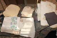 Assorted towels folded on couch showing white, cream, and embroidered floral designs