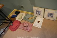 Overall view of assorted napkins, placemats, two wooden art frames, and napkin rings positioned on floor near corner.