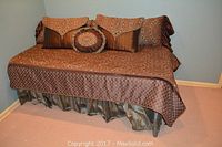 Twin bed frame dressed with brown patterned bedding and matching pillows in a bedroom corner.