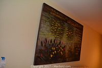 Large canvas painting on wall showing water lilies and lily pads, colors green, yellow, red on dark background.