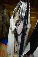 Side view of assorted formal dresses hanging on hangers showing variety of colors and styles.