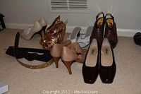 Six pairs of ladies shoes and two belts arranged on carpet, showing various styles and colors.
