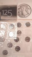 Two packs of 10 uncirculated Stanley Cup quarters in plastic wrap, with the presentation folder showing '125 Years' and the Stanley Cup design.