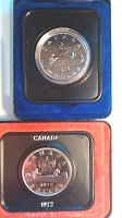 Close up of 1972 and 1976 Canadian canoe silver dollar coins in individual blue and red cushioned black leather-like clam shell cases.