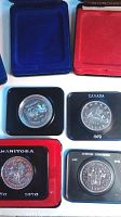 Four Canadian silver dollar coins in individual display cases in red, blue, and black colors, clearly showing the years 1970, 1971, 1972, and 1974.