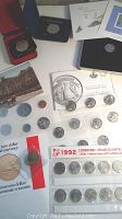 Full view of various coins and coin sets including silver dollars, quarters and specimen sets on display.
