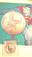 Photo showing the front and part of the booklet with Superman image and coin displaying the raised Superman figure with date 2015 and silver purity markings.