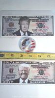 2016 and 2017 Donald Trump commemorative bills laid out flat with the silver coin placed between them, measuring about 1.75 inches in diameter.