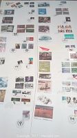 Photo of about 24 Canadian first day covers arranged in two vertical columns on white surface. Stamps and envelopes display various themes and illustrations.