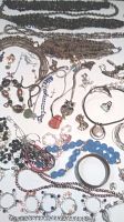Overview of assorted beaded necklaces, rings, bracelets, and earrings on white background.