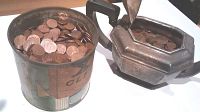 Two containers shown filled with Canadian pennies, one a vintage hand cleaner tin and the other an old coffee pot.