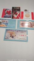 Various Canadian coins and bills displayed on a flat surface illustrating the lot contents including folders and individual coins.
