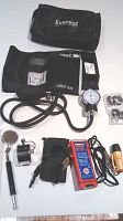 Top view of adult sphygmomanometer blood pressure gauge with cuff, inflation bulb, gauge, Everest branded black carry bag and replacement rubber washers, plus other included items in the lot.
