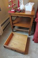 Pair of vintage wooden end tables shown with various small decorations on top, one drawer on the floor in front of one table.
