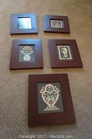 Five framed Scherenschnitte artworks arranged on floor