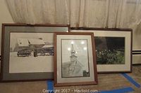 Three framed prints leaning against wall showing wagon scene, church steeple, and landscape