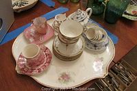 Tea cups and saucers on floral decorated platter with gold edging