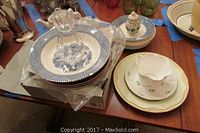 Angle showing clear Wedgwood glass pitcher on top of blue and white plates, along with shamrock-patterned cup and saucer and other plates on the side.