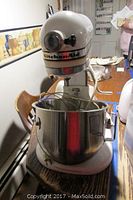 Full view of Kitchen Aid stand mixer on table with mixing bowl attached.