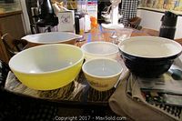 Five mixing bowls arranged on a wooden table.