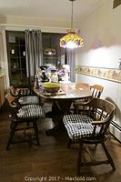 Full view of pine hunt country wooden dining table with five matching chairs with black and white checkered cushions in dining room.