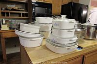 Stack of Corning Ware bakeware dishes including both Cornflower and French White patterns on kitchen counter.