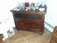Full view of wood storage cabinet with open shelf and two doors, dark brown finish, on wood floor.