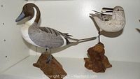 Side view of the two carved birds on wood bases, showing detailed paint and carving