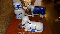 Three Eldreth Pottery animal figures: cat, lamb, and cow, on table