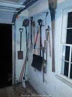 Wall-mounted yard tools including shovels, post digger, fork, popper, and bulb hole digger