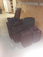 Six pieces of luggage arranged on floor: three smaller rolling carry-on bags and three larger rolling check-in bags