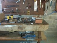 Workbench with assorted round saw blades, rolls of tape, clamps, files, and other small hand tools.