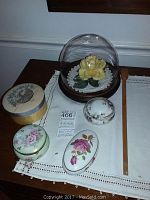 Full lot of trinket boxes and Peace Rose dome displayed on tablecloth