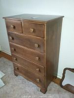 Front view of the six-drawer maple dresser showing the wooden round pulls and overall shape.