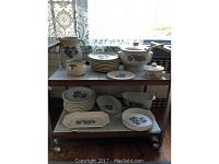 Full view of Pfaltzgraff dinnerware set displayed on cart, showing plates, covered tureen, serving bowls, and trays.
