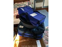 Stack of four blue and black carrying cases with contents inside, likely Pyrex cookware sets