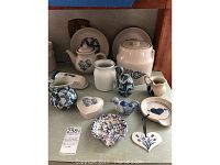 Full display of Pfaltzgraff pottery items on shelf including cookie jar, tea pot, pitchers, plates and decorative pieces.