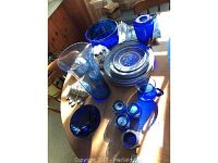 Blue glass dinnerware, serving platter, candleholders, vases, and pitcher arranged on a round table.