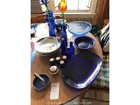 View of lot showing cobalt blue glassware including platter, vases, medicine bottles, candle holder, and Premiere China bowls with floral patterns.