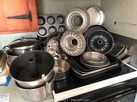 Overview of assorted bakeware including bundt pans, cupcake pans, and large cooking pot on stovetop.