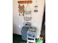 Photo of wooden coat rack mounted on wall, hand-painted welcome sign with snowman, gray painted mailbox box, rolling cart with three trays, and hanging wire baskets.