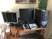 Full view of Dell desktop, dual monitors, keyboard, mouse, speakers, and setup disks on wooden desk