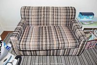 Front view of vintage plaid loveseat sleeper showing upholstery and cushion condition.