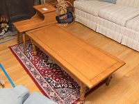 Photo showing the two wooden tables and the accent rug underneath, positioned near sofas in a living room setting.